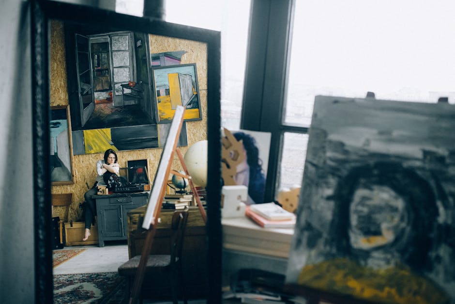 An art studio featuring paintings, a mirror reflection of a woman, and creative elements.