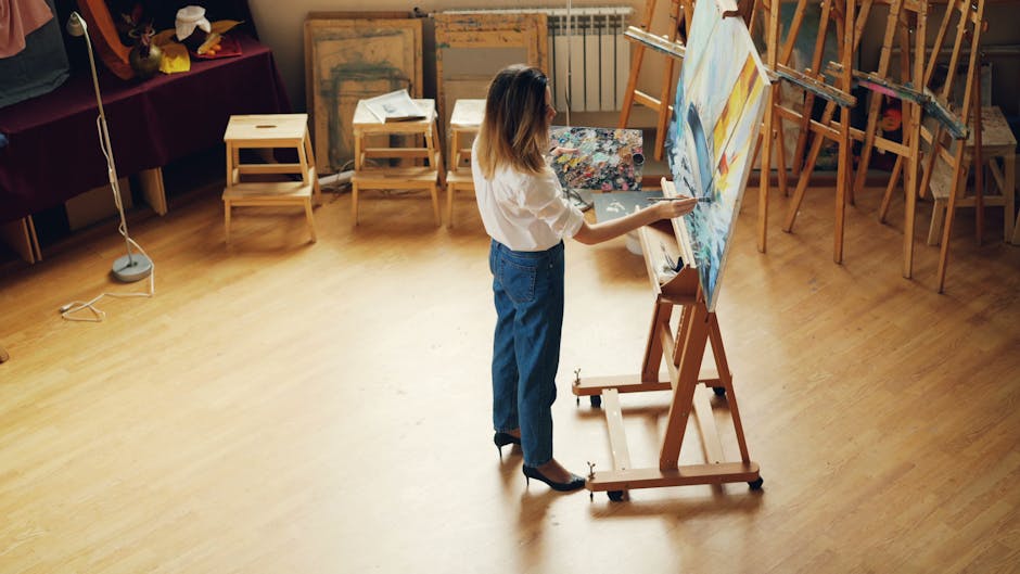 Woman painting on canvas in art studio, creating a vivid landscape artwork.